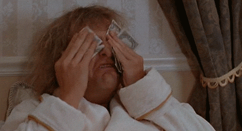 A man wipes his face with dollar bills.